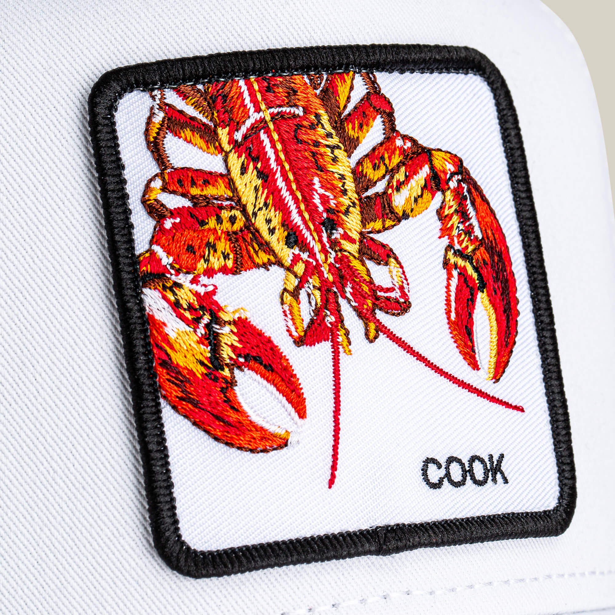 A close-up of the Goorin Bros. Lemme Cook Mini hat, a kid-sized cap featuring a playful lobster patch.