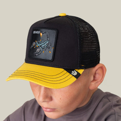 A boy wearing the Goorin Bros. Deadly Mini kids hat with a yellow brim, featuring a scorpion patch and "DEADLY" embroidered on the front.