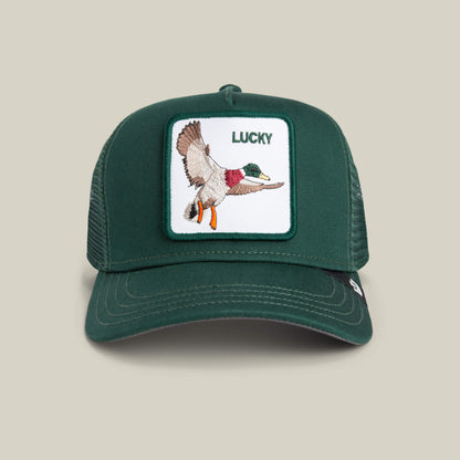 The Goorin Bros. Lucky Duck Mini is a kid-sized green trucker hat with a mesh back, white front featuring a flying duck patch and "LUCKY" embroidery, finished with a classic green crown.