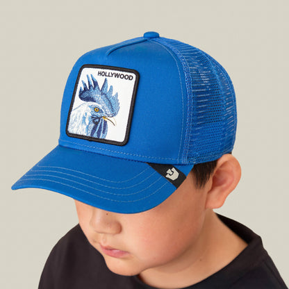 A boy wearing the Goorin Bros. Hollywood Rooster Mini blue mesh cap and electric blue shoes looks downward against a plain background.