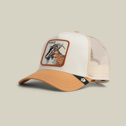 The Goorin Bros. Goat Trucker Mini features a white cotton front panel and cream mesh back with an embroidered goat patch in tan and brown, orange trim, and an adjustable snapback closure, displayed against a neutral background.