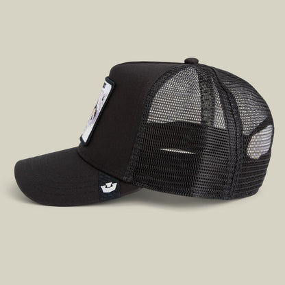 The Goorin Bros. Bandit Trucker Mini is a black trucker hat with mesh back panels, featuring a small white patch on the front and a snapback closure, photographed against a neutral beige background.