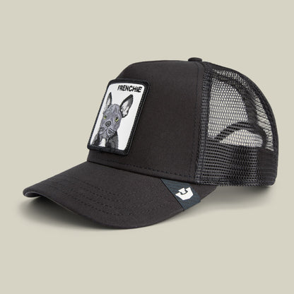 The Goorin Bros. Frenchie Trucker Mini is a black mesh-back snapback cap featuring a white patch with a French Bulldog illustration and text reading "FRENCHIE" on the front, shown against a neutral beige background.
