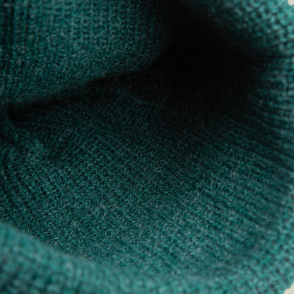 Close-up view of the inside of The Playful Beanie Mini by Goorin Bros., showing cozy green knit fabric and detailed stitching.
