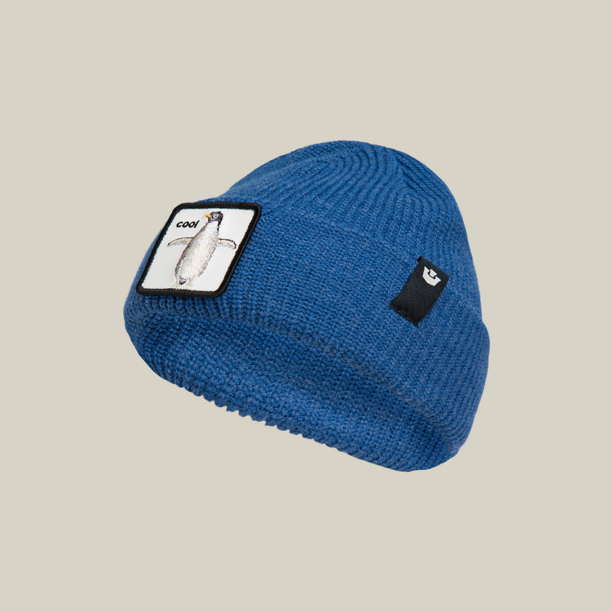 The Penguin Beanie Mini by Goorin Bros. is a blue knit kids hat with a playful penguin patch and a black logo label—ideal for adding warmth and style on snow days.