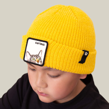 A child wears The Curious Beanie Mini by Goorin Bros., a bright knit kids beanie featuring a playful cat patch with a curious face on the front.
