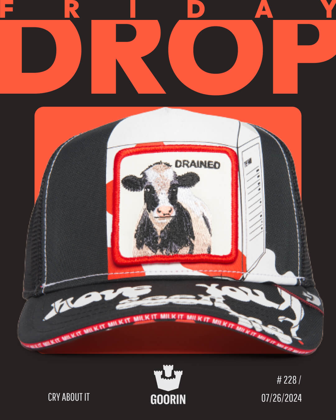 A black mesh trucker hat with a patch of a cow labeled DRAINED on the front, set against a bold orange and black background with the text FRIDAY DROP—perfect for those who love bold hat designs.