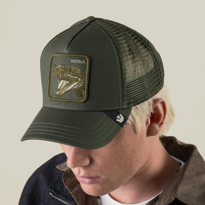 A person wearing the Goorin Bros. Circle of Life - Vicious trucker hat, featuring a dark green design with an open-mouthed animal patch and the word “VICIOUS” on the front, looks downward against a plain background. This olive mesh baseball cap offers a breathable back and an adjustable snapback for comfort.