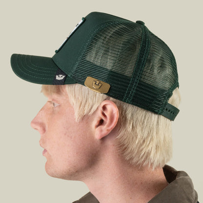 A person with light blond hair is wearing a dark green mesh Goorin Bros. baseball cap, styled with the sleek zinc alloy Castle CapLoc brim clip accessory, seen from the side against a plain background.
