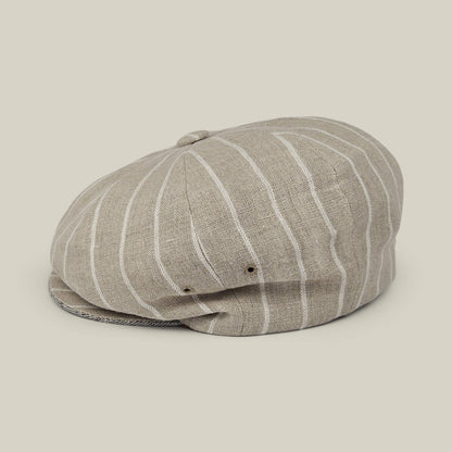 Introducing the Rincon Park by Goorin Bros.—a beige, linen blend newsboy cap showcasing a classic Gatsby silhouette with white vertical stripes, a signature top button, and dual side ventilation holes. Each piece is expertly hand cut and sewn for lasting quality.