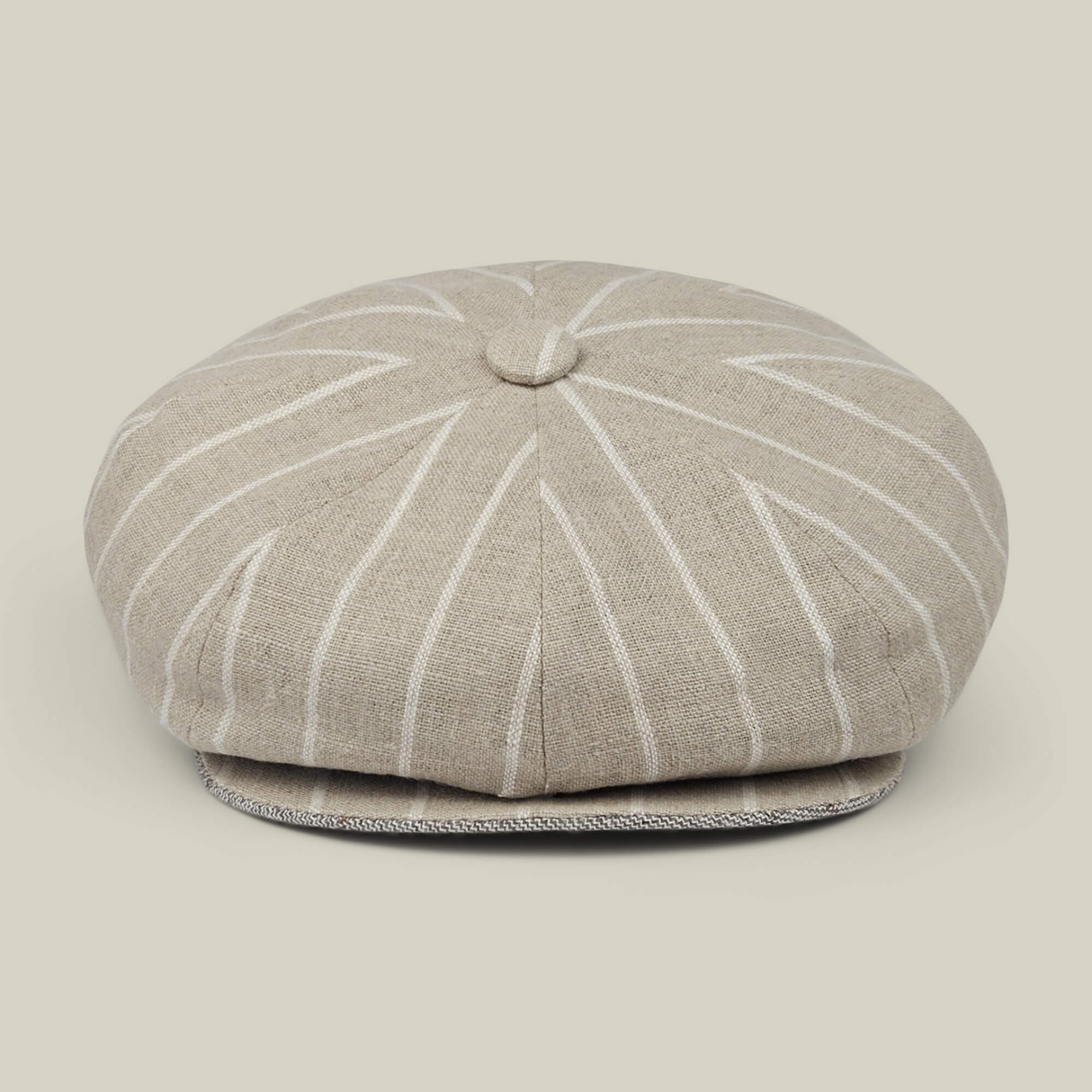 The Rincon Park by Goorin Bros. is a beige linen blend newsboy cap with white pinstripes, featuring a classic Gatsby silhouette with a button on top and a short, curved brim. Each cap is hand cut and sewn, and it is displayed against a neutral background.