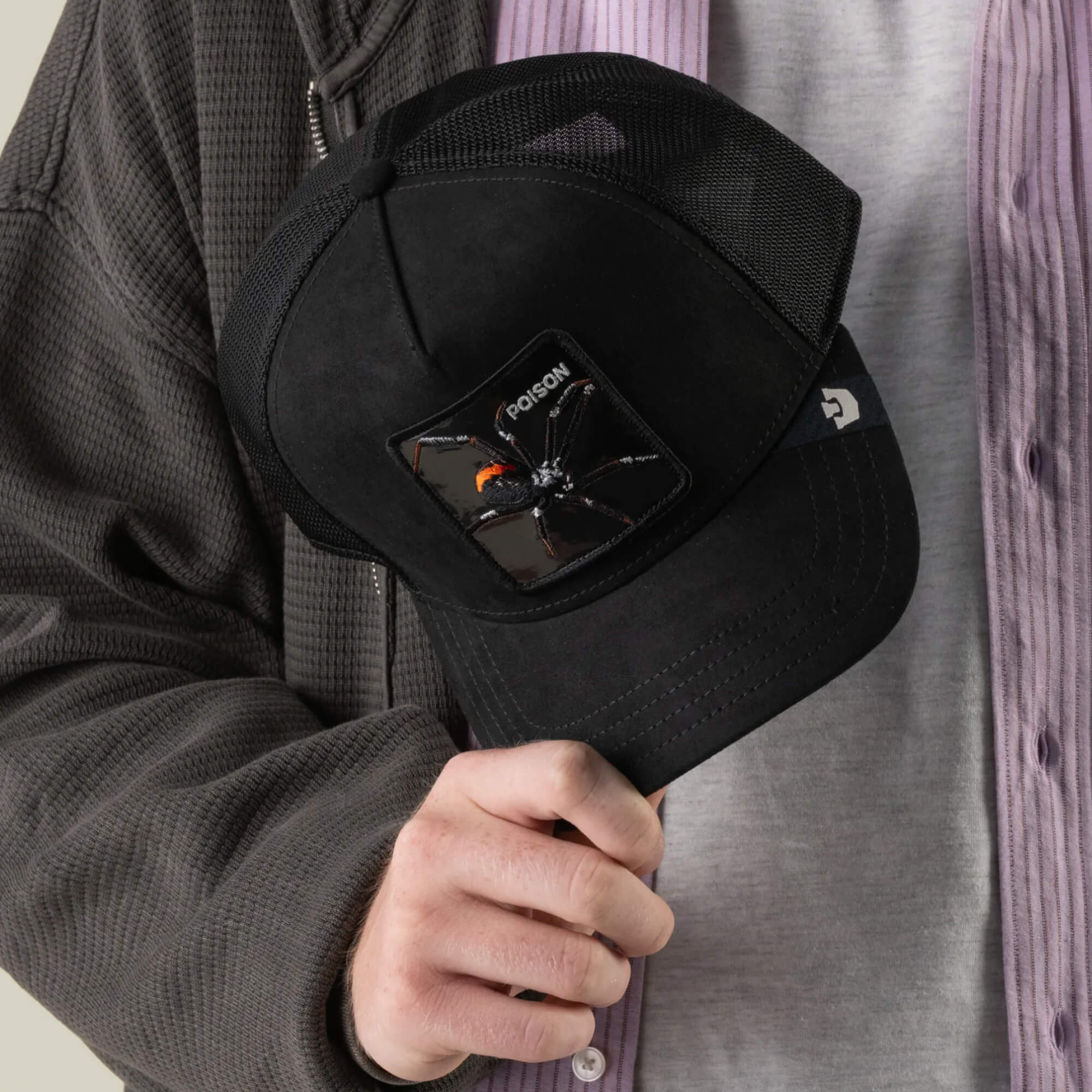 A person holding the Goorin Bros. Black Out Spider baseball cap, featuring an embroidered spider patch and the word “POISON” on the front—channeling true blackout spider energy.
