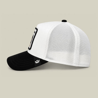 The Goorin Bros. Suede Alpha trucker hat features a white mesh back panel, black suede front bill, and a black carabiner clip accent on the side, displayed against a neutral studio background.