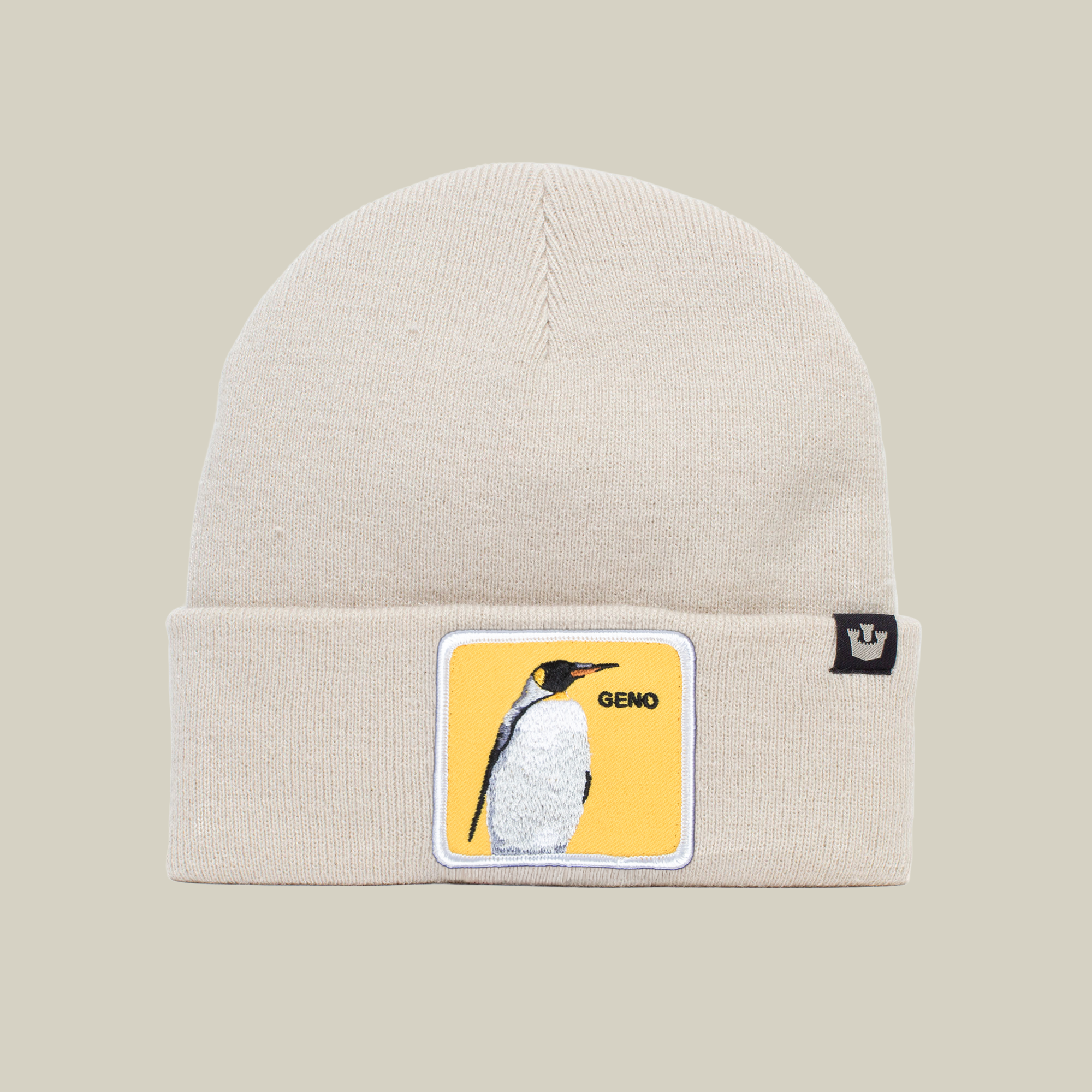 The Farm’s Warm Geno beanie in creme features a yellow patch with an illustrated penguin and GENO, honoring Pittsburgh legend Evgeni Malkin, plus a small black cuff tag with a crown logo.