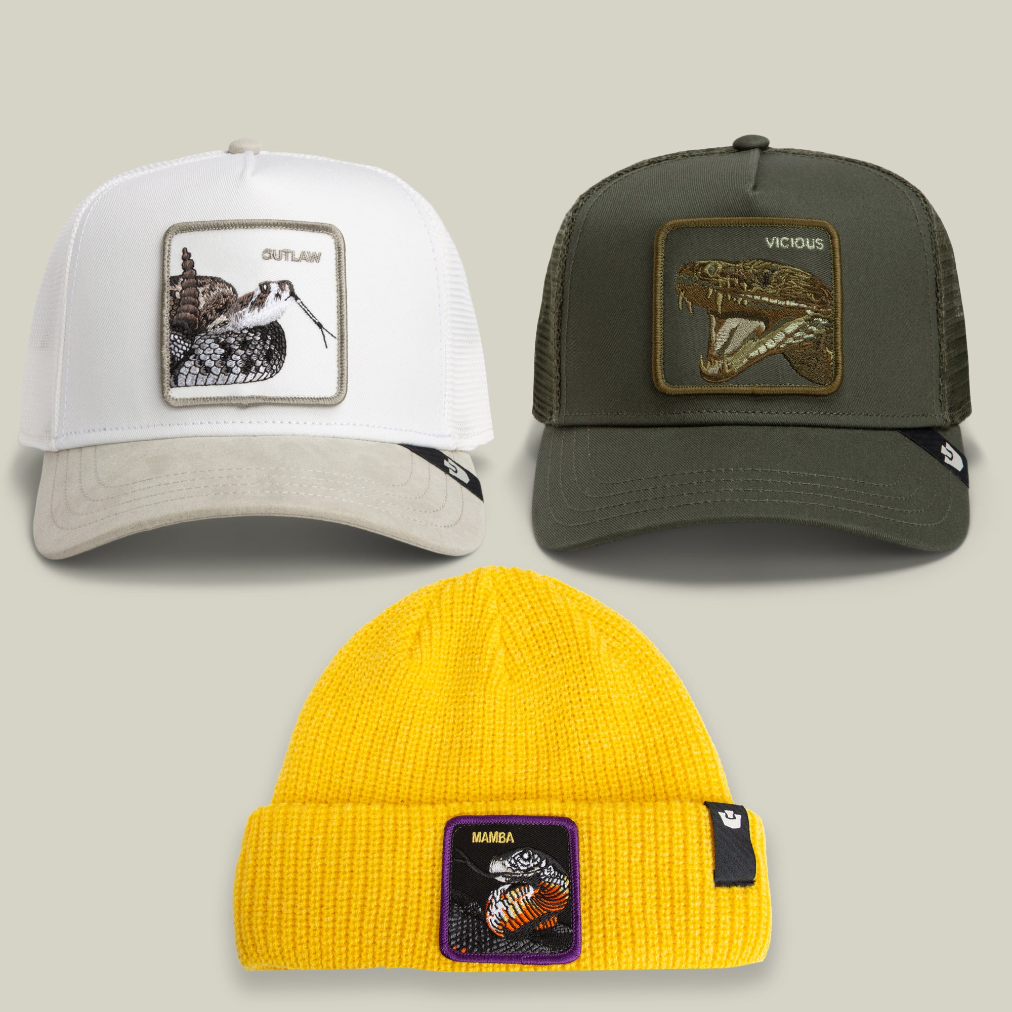 The Slither Me Timbers Bundle by Goorin Bros. features two trucker hats—one white and one green, both with snake patches—arranged above a yellow beanie adorned with a bee patch, all set against a neutral background.