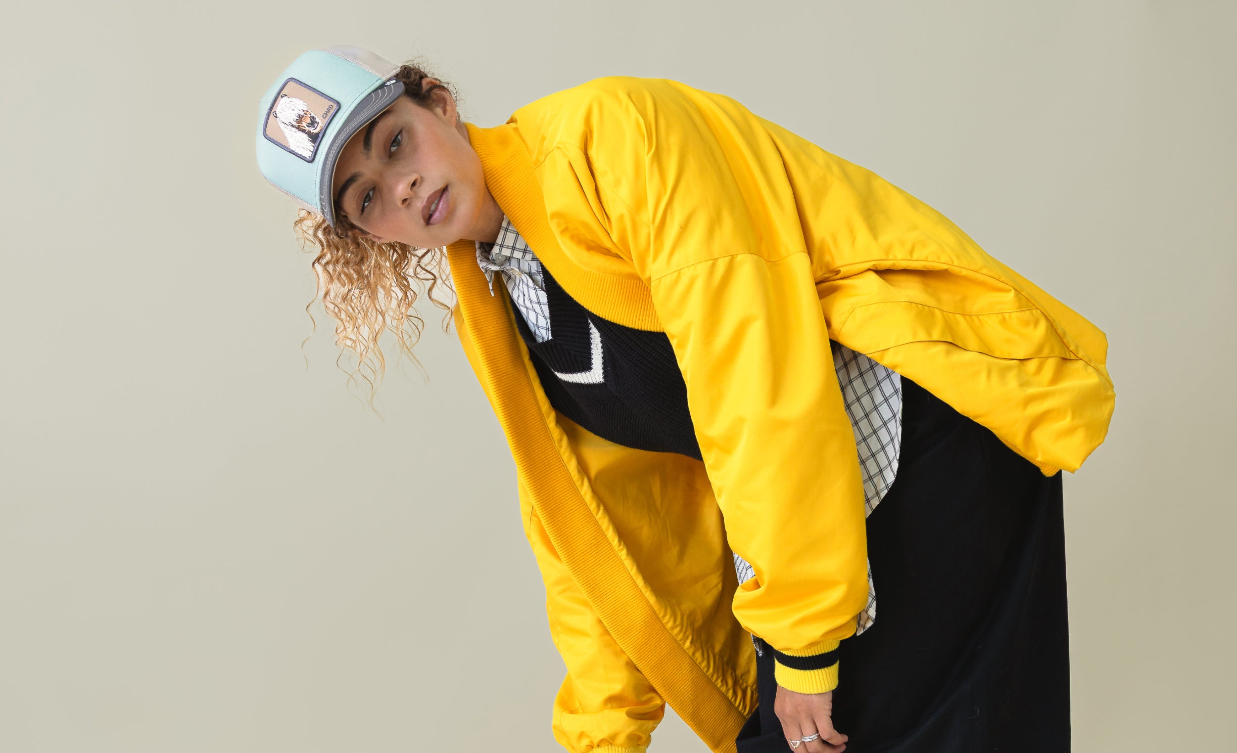 Person wearing a yellow raincoat and cap on a plain background