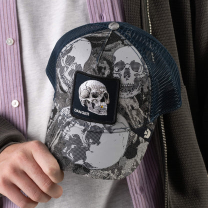 A person holds the Goorin Bros. Bone Head Danger cap, featuring a striking skull print and a patch embroidered with a skull and the word “DANGER.”.