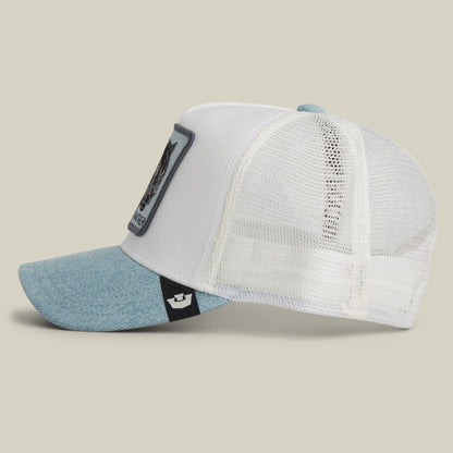 The Goorin Bros. Denim Panther is a white mesh trucker hat with a light blue denim brim, a side patch, and a front patch featuring a bear graphic, shown in side profile on a light background.