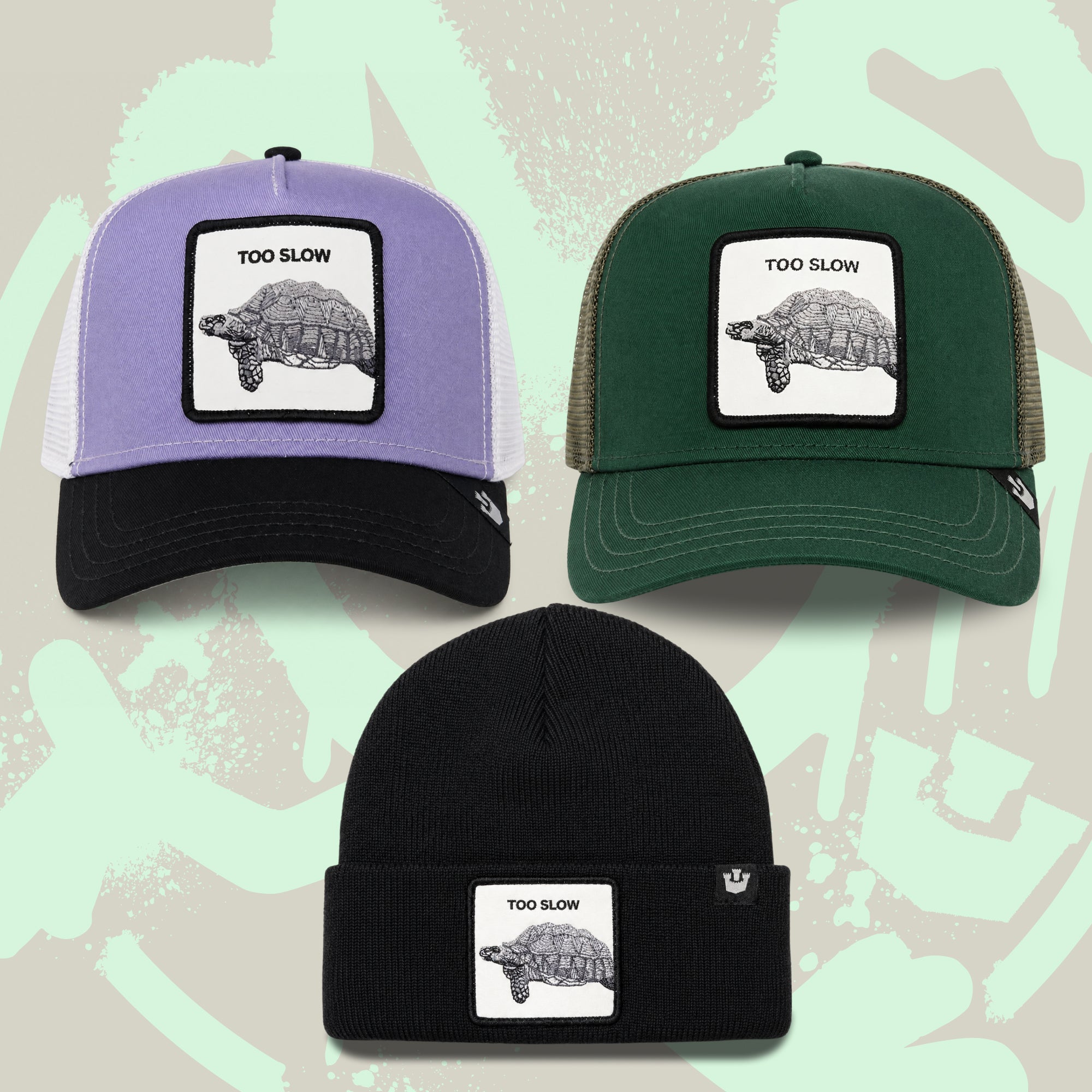 The Down Low Bundle by Goorin Bros. features three hats with TOO SLOW patches and a tortoise illustration: two trucker caps (one purple, one green) and a black beanie—each piece is a limited-edition badge of honor, presented on a light abstract background.