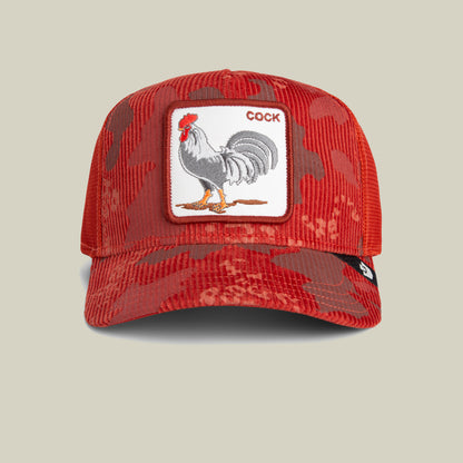 The Goorin Bros. Rooster Camo is a red camouflage trucker cap featuring a front patch with an illustration of a rooster and the word “COCK” above it, along with a small black side tag for added detail.