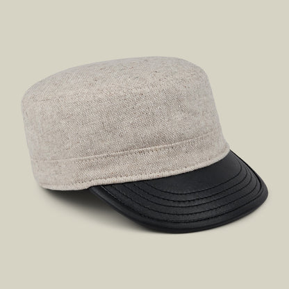 The Goorin Bros. South Boulder cadet cap, crafted from beige wool and leather and hand cut and sewn in the USA, features a short, curved black faux leather brim and is displayed on a plain light background.