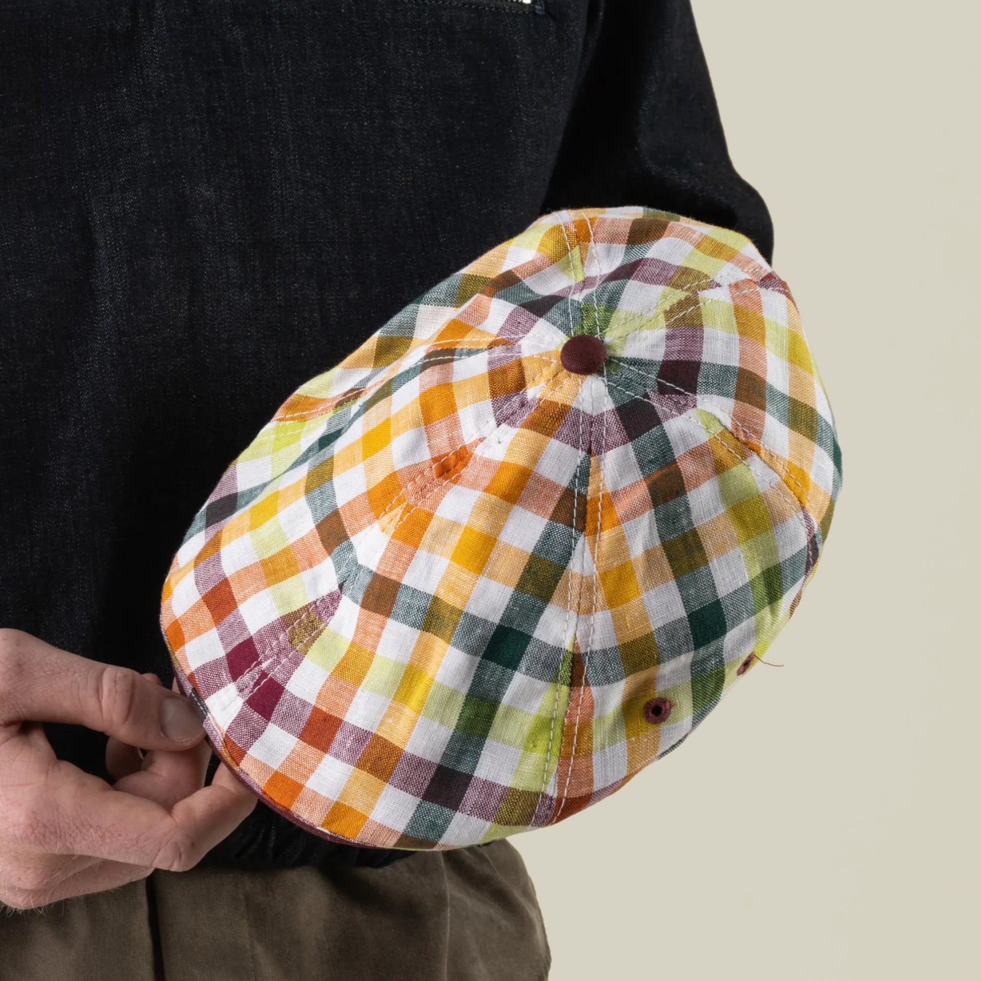 A person holding the Goorin Bros. Point Lobos cap—a classic 6 Panel Ivy style crafted from a breathable cotton blend and featuring a vibrant plaid pattern in yellow, green, red, and white checks—set against a neutral background.