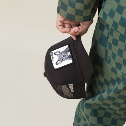 Someone holding the Goorin Bros. Frenchie Trucker—a cute black cap featuring a dog face patch and the word "FRENCHIE"—while dressed in a green checkered outfit.