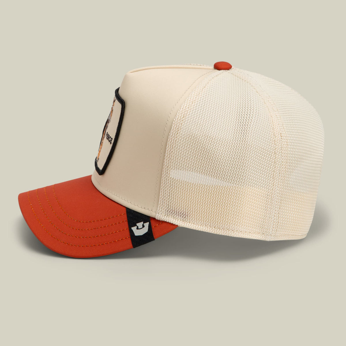 The Goorin Bros. Migration - Fierce trucker hat features a cream and red colorblock design with a mesh back panel, small red ornamental bead accent, and brand patch on the front, displayed against a neutral studio background.